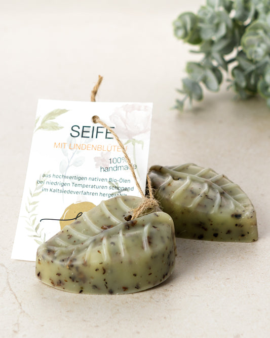 Handgemachte Peeling-Lindenblütenseife mit Lavendel- und Geranienduft mit Etikett mit hochwertigen Inhaltsstoffen und Anwendungshinweisen und Deko- Zutaten im Text beschrieben