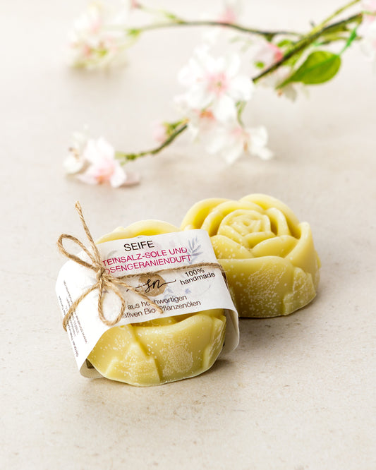 Handgemachte Steinsalzsoleseife mit Rosengeranienduft mit Etikett mit hochwertigen Inhaltsstoffen und Anwendungshinweisen und Deko- Zutaten im Text beschrieben