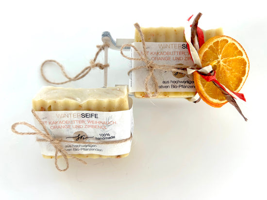 Für die Wintersaison packen wir die Winterseife auf einen weißen Holz Schlitten und einer 2. Seife 
mit Papier-Bastband und einer getrockneten Orangenschale als Dekoelemente von oben